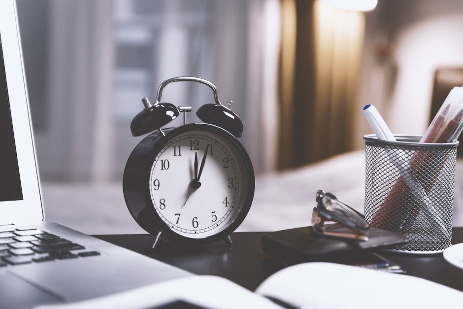 An analog clock on a desk next to study notes.
